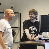 Programmeurs lachen met elkaar voor een bureau op kantoor.